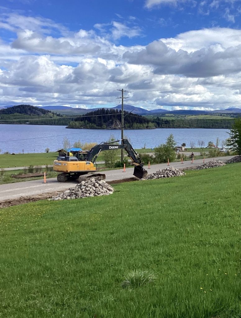 Excavator distributing riprap in Fraser Lake for civil infrastructure project