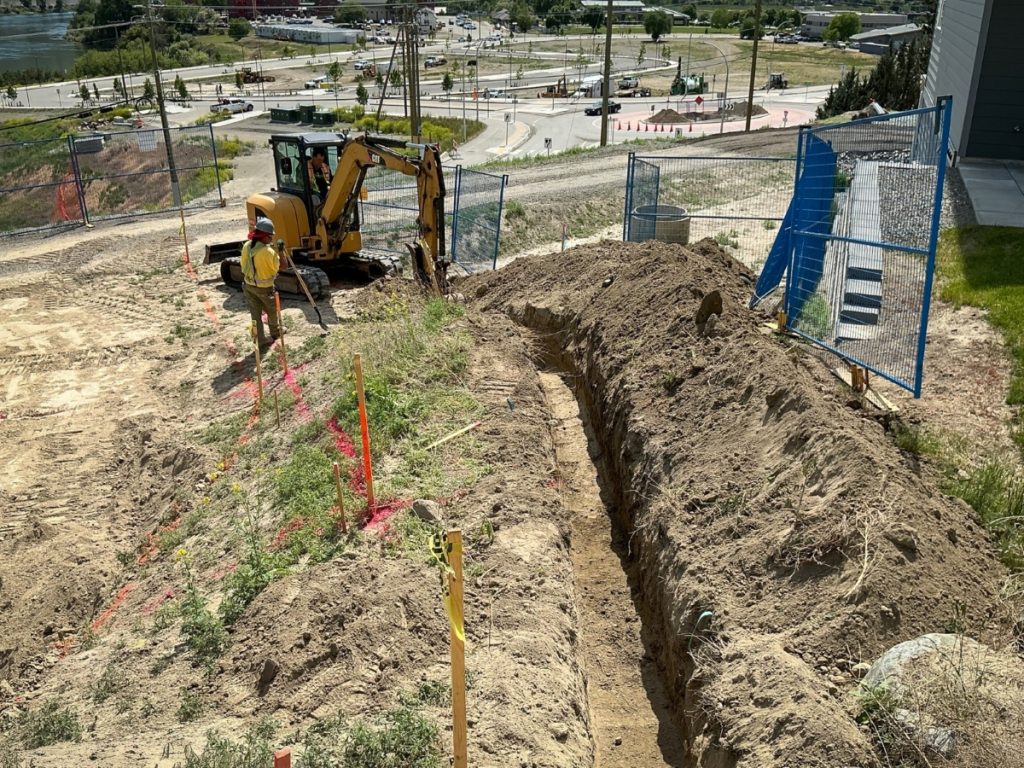 Dawson Civil excavator and crew excavating underground utilities at the Sagewood Booster Station construction site in Sun Rivers, Kamloops, BC.