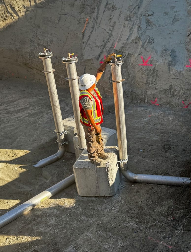 Dawson Civil crew member inspecting underground piping and concrete pad installation at the Sagewood Booster Station construction site in Kamloops, BC.